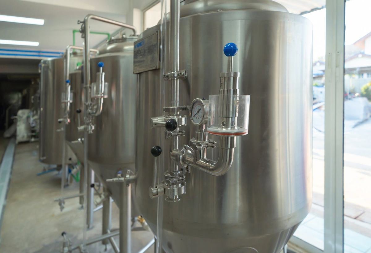 Przenośnik taśmowy i zbiorniki ze stali nierdzewnej w hali produkcyjnej